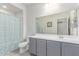 Bright bathroom featuring a shower with a stylish blue shower curtain and a well-lit vanity with gray cabinets at 16221 W Prickly Pear Trl, Surprise, AZ 85387