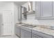 Bright kitchen with stainless steel range hood, gray cabinets, and sleek cooktop at 16221 W Prickly Pear Trl, Surprise, AZ 85387