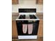 Close-up of a black and white kitchen stove with hanging towels and tile floors at 1714 W Villa Rita Dr, Phoenix, AZ 85023