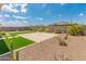 Landscaped backyard featuring low-maintenance desert landscaping, decorative rock, a patch of artificial turf, and a stone patio at 17886 W Brookwood Dr, Goodyear, AZ 85338