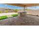 Covered outdoor patio featuring built-in BBQ, travertine tile flooring, artificial turf, and desert landscaping at 17886 W Brookwood Dr, Goodyear, AZ 85338