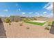 Landscaped backyard featuring low-maintenance desert landscaping, decorative rock, a small patch of artificial turf, and a stone patio at 17886 W Brookwood Dr, Goodyear, AZ 85338
