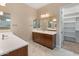 Modern bathroom featuring dual sinks, wooden cabinets, and large mirrors at 17886 W Brookwood Dr, Goodyear, AZ 85338