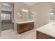 Well-lit bathroom with double sinks, white countertops, and tile flooring, exuding elegance at 17886 W Brookwood Dr, Goodyear, AZ 85338