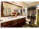 Bathroom featuring double sinks, dark wood cabinetry, large mirror, and decorative accents at 2171 E Iris Dr, Chandler, AZ 85286