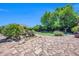 Scenic backyard featuring a stone patio, mature trees, and tranquil water feature at 2383 E Zion Way, Chandler, AZ 85249