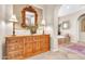 This is a hallway view to the primary bathroom with a large wood dresser with a mirror and lamps at 2383 E Zion Way, Chandler, AZ 85249