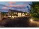 Backyard at dusk with gravel, mature trees, and covered patio at 4571 N Arbor Way, Buckeye, AZ 85396