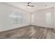 A blank room featuring hard floors, a modern ceiling fan and dual windows at 4571 N Arbor Way, Buckeye, AZ 85396