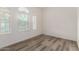 A vacant room features hard floors, neutral colored paint, and 3 windows at 4571 N Arbor Way, Buckeye, AZ 85396