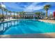 Community swimming pool offers recreational water features, lounge chairs, and palm trees under a bright blue sky at 4571 N Arbor Way, Buckeye, AZ 85396