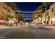Nighttime scene of a street adorned with lights, commercial buildings, and parked cars at 4571 N Arbor Way, Buckeye, AZ 85396