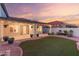 Serene backyard featuring an artificial lawn surrounded by decorative rock, enhanced with potted plants and string lighting at 47 W Calle Monte Vis, Tempe, AZ 85284