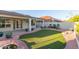 Beautiful backyard featuring an artificial lawn surrounded by decorative rock and potted plants, with a covered patio at 47 W Calle Monte Vis, Tempe, AZ 85284