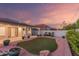 Well-manicured backyard with an artificial grass area, decorative rock landscaping, and ambient string lighting for evening enjoyment at 47 W Calle Monte Vis, Tempe, AZ 85284