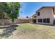 Expansive backyard with grassy area, block fence, covered patio, and rear house view at 4948 W Wikieup Ln, Glendale, AZ 85308