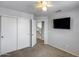 Neutral bedroom featuring a ceiling fan, TV, closet, and doorway leading to the upper level at 4948 W Wikieup Ln, Glendale, AZ 85308