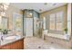 Bathroom with dual sinks, soaking tub, glass-enclosed shower, and neutral tile at 7418 E Black Rock Rd, Scottsdale, AZ 85255