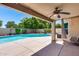Covered back patio featuring a ceiling fan, pavers, a light-colored wall, and a view of the pool and backyard at 7435 W Trails Dr, Glendale, AZ 85308