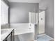 Modern bathroom showcasing a bathtub, a shower with a glass door, and a vanity sink under a window at 7435 W Trails Dr, Glendale, AZ 85308