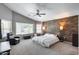 Bright main bedroom with a wood accent wall, ceiling fan, and large windows creating a serene atmosphere at 7435 W Trails Dr, Glendale, AZ 85308