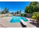 A swimming pool features a diving board, and a basketball hoop with a view of the backyard and blue skies at 7435 W Trails Dr, Glendale, AZ 85308