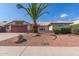Charming single-story home features desert landscaping, a palm tree, and a red two-car garage at 7526 W Windrose Dr, Peoria, AZ 85381