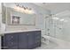 Updated bathroom featuring a blue vanity, framed mirror, and glass-enclosed bathtub with shower at 9450 E Becker Ln # 1046, Scottsdale, AZ 85260