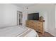 Bedroom featuring wood floors, a large screen TV on a wooden dresser, and an open doorway to another room at 9450 E Becker Ln # 1046, Scottsdale, AZ 85260