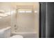 Bright bathroom featuring a tub-shower combination with tiled walls and a window at 1655 W Stanford Ave, Gilbert, AZ 85233