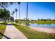 Scenic view of a paved path near a lake lined with lush greenery and tall palm trees under a clear blue sky at 1655 W Stanford Ave, Gilbert, AZ 85233