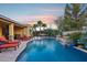 Serene backyard with pool, lounge area, and desert landscaping, creating a relaxing outdoor living space at dusk at 19002 N Arbor Dr, Maricopa, AZ 85138