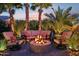 Outdoor firepit area with cozy seating, surrounded by lush landscaping and soft lighting at twilight at 19002 N Arbor Dr, Maricopa, AZ 85138