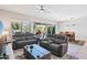 Spacious living room with leather furniture, a ceiling fan, and natural light from the backyard sliding doors at 19002 N Arbor Dr, Maricopa, AZ 85138