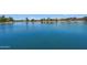 Scenic community pond with tranquil blue water, surrounded by lush landscaping and clear skies at 19002 N Arbor Dr, Maricopa, AZ 85138