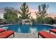 Serene backyard featuring a refreshing pool with water features, surrounded by lush greenery and lounge chairs for relaxation at 19002 N Arbor Dr, Maricopa, AZ 85138