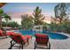 Beautiful pool area with water feature, surrounded by lounge chairs and lush landscaping at sunset at 19002 N Arbor Dr, Maricopa, AZ 85138