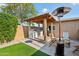 Backyard showcasing the outdoor kitchen, barbecue area, and comfortable seating with a grassy area at 19615 N 18Th Dr, Phoenix, AZ 85027