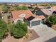 Aerial view of home featuring desert landscaping, a tile roof with solar panels, and a three-car garage at 21532 N 262Nd Ln, Buckeye, AZ 85396