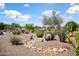 Lush desert landscaping with rock features creates a serene backyard environment on a sunny day at 21532 N 262Nd Ln, Buckeye, AZ 85396
