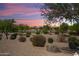 Scenic community view with lush landscaping, a tranquil pond, and vibrant sunset hues in the sky at 21532 N 262Nd Ln, Buckeye, AZ 85396