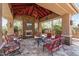 Outdoor covered patio featuring stone fireplace, seating area, television, and relaxing ambiance at 27421 N 22Nd Ln, Phoenix, AZ 85085