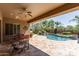 Charming covered patio with a dining table and chairs overlooking a beautiful pool with a rock waterfall at 27421 N 22Nd Ln, Phoenix, AZ 85085