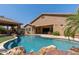Backyard pool featuring a rock waterfall, covered patio, and lush landscaping, perfect for relaxation and outdoor enjoyment at 27421 N 22Nd Ln, Phoenix, AZ 85085