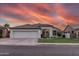 Charming single-story home boasts a well-manicured lawn, three-car garage, and delightful curb appeal under a vibrant, colorful sunset sky at 2982 S Holguin Way, Chandler, AZ 85286
