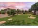 Large backyard with green grass, a putting green, play structure, and mature trees at 6299 S Roanoke St, Gilbert, AZ 85298