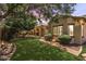 Backyard featuring lush landscaping, a covered patio, trees, and a winding brick path at 6299 S Roanoke St, Gilbert, AZ 85298
