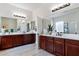 Spacious bathroom with dual vanities, dark wood cabinets, large mirrors, and neutral decor at 6299 S Roanoke St, Gilbert, AZ 85298