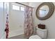 Bright bathroom with a shower-tub combo and a round mirror above the toilet at 6299 S Roanoke St, Gilbert, AZ 85298