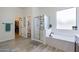 Well-lit bathroom featuring a glass-enclosed shower, soaking tub, and a view into the walk-in closet at 6299 S Roanoke St, Gilbert, AZ 85298